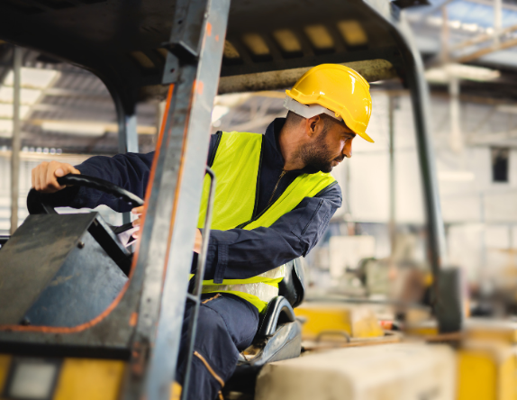 male warehouse worker backing up a forklift