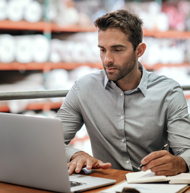warehouse manager sitting at a desk using a laptop